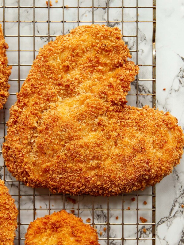 overhead shot of heart shaped chicken on wire rack above marble backdrop