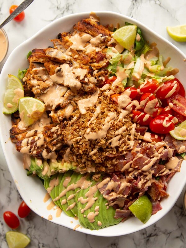 overhead shot of grilled chicken salad in large white serving bowl on marble background