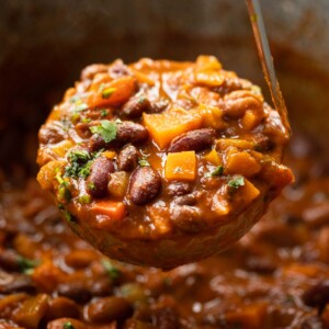 close up shot of ladle scooping out 3 bean chilli from large pot