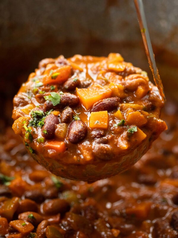 close up shot of ladle scooping out 3 bean chilli from large pot