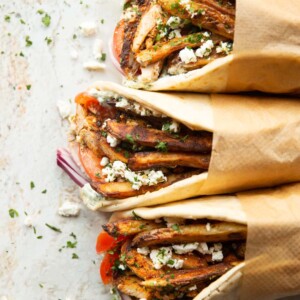 overhead shot of 3 chicken gyros wrapped in brown parchment paper