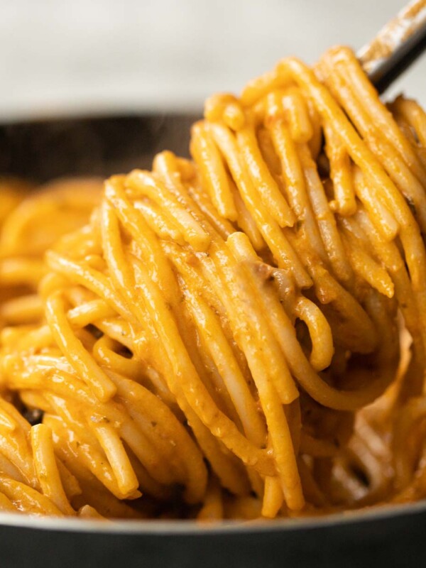 close up shot of tongs twisting pasta in pan