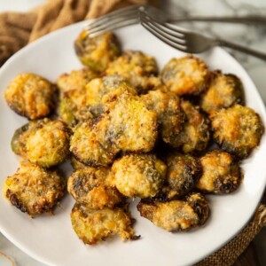 smashed brussels sprouts on small white plate with two silver forks