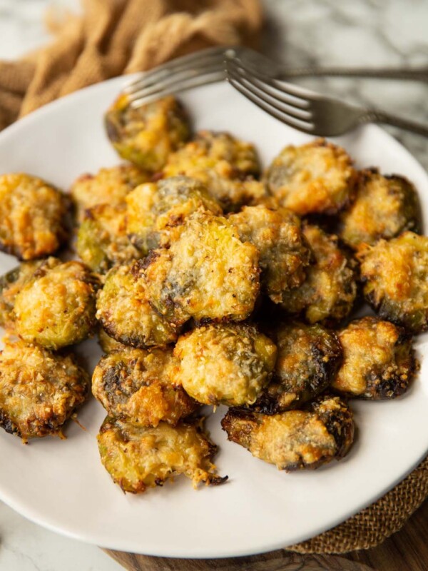 smashed brussels sprouts on small white plate with two silver forks