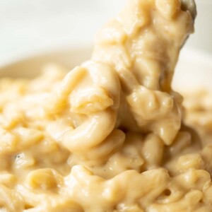 close up shot of fork digging into small white bowl of mac and cheese