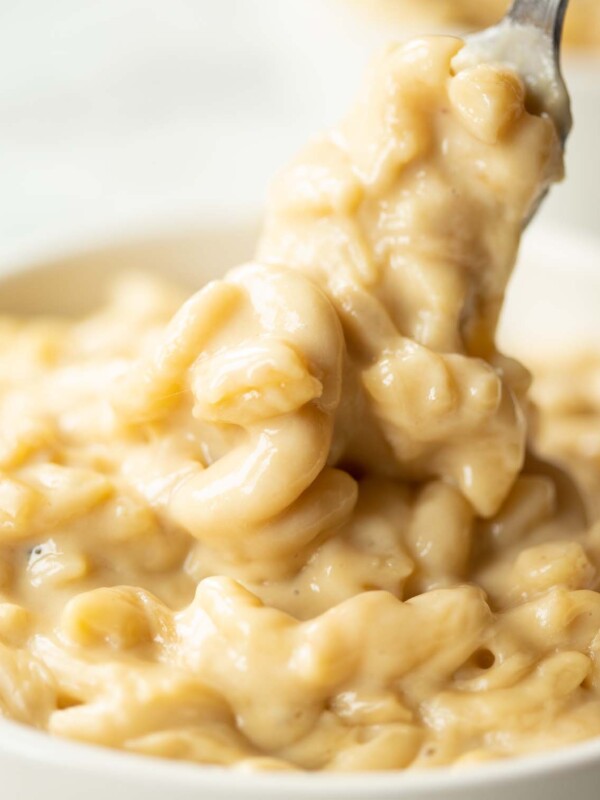 close up shot of fork digging into small white bowl of mac and cheese