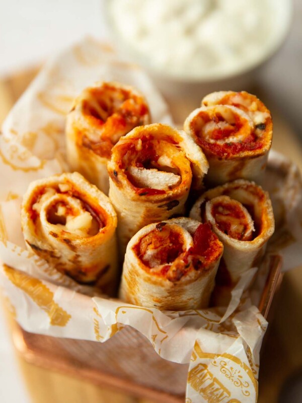 6 pizza roll ups in a small pot with dip blurred in the background