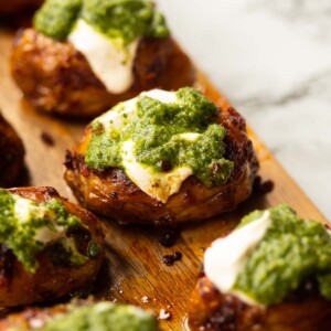 close up shot of pesto nduja potato on wooden chopping board