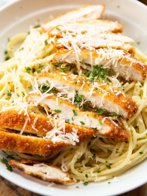 close up shot of garlic chicken pasta served with parmesan and parsley in white dish