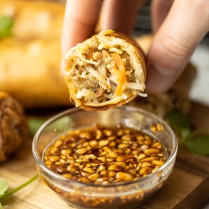 close up shot of hand holding half a Thai spring roll showing filling