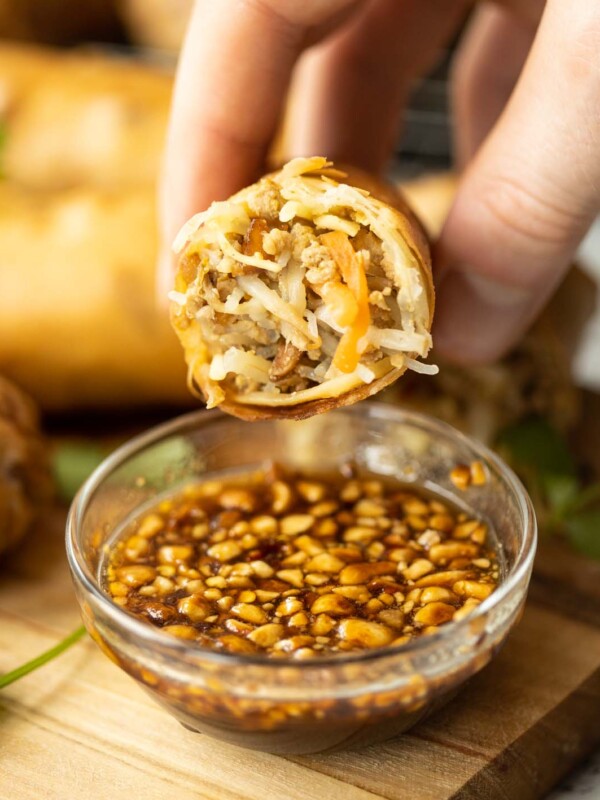 close up shot of hand holding half a Thai spring roll showing filling