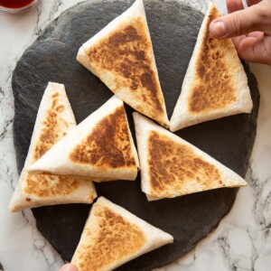 overhead shot of 6 breakfast pockets on slate with two hands grabbing one each