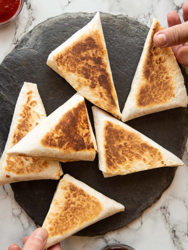 overhead shot of 6 breakfast pockets on slate with two hands grabbing one each