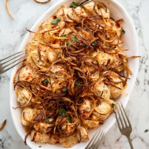 overhead shot of cajun potato salad in large white serving dish with 4 silver forks