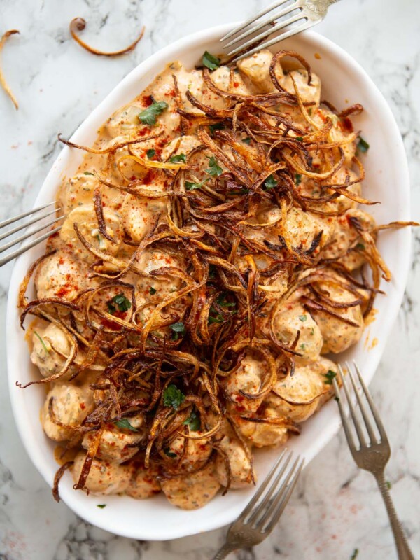 overhead shot of cajun potato salad in large white serving dish with 4 silver forks