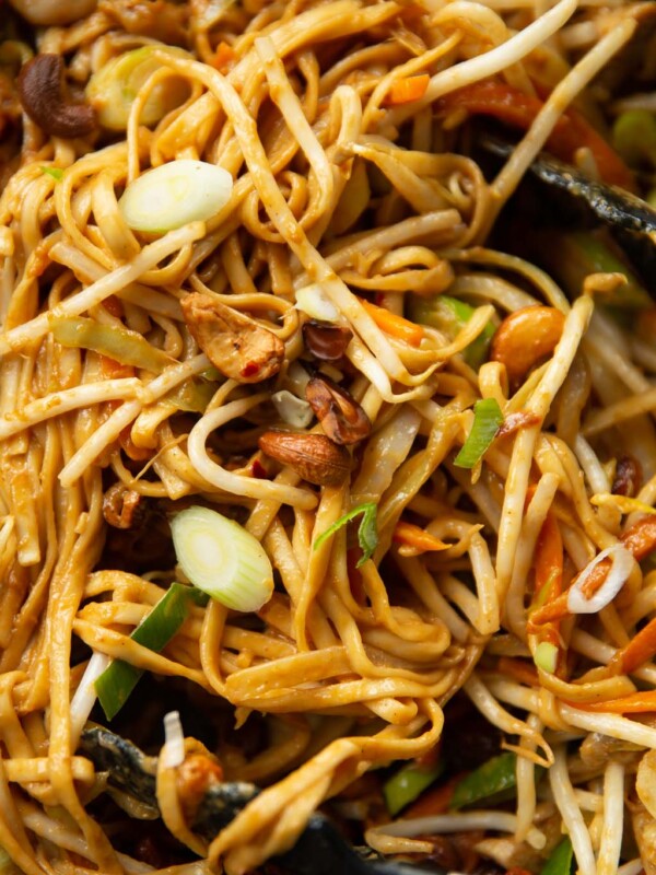 close up shot of cashew chicken stir fry in wok with tongs digging in