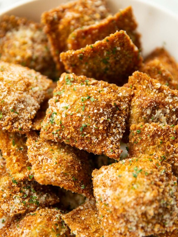 close up shot of toasted ravioli in large white dish