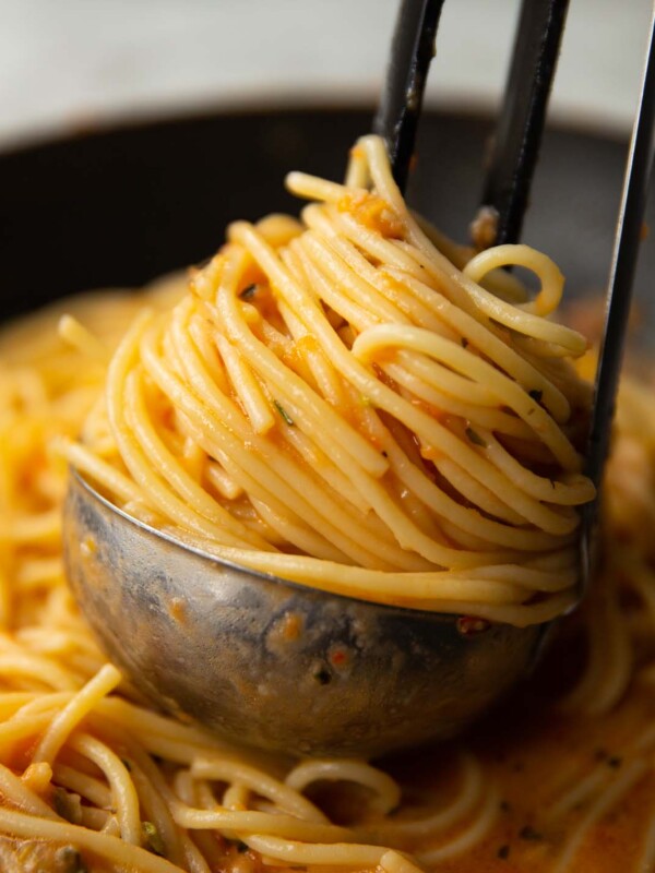 close up shot of tomato butter pasta in silver ladle