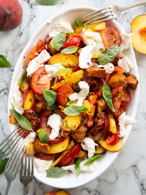 overhead shot of tomato peach salad in large white dish garnished with fresh basil