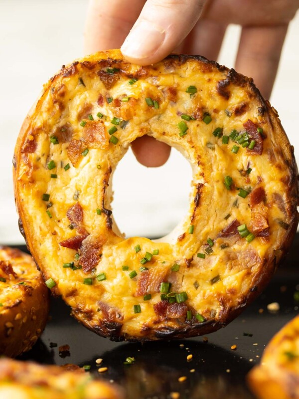 close up shot of hand holding bagel above baking tray