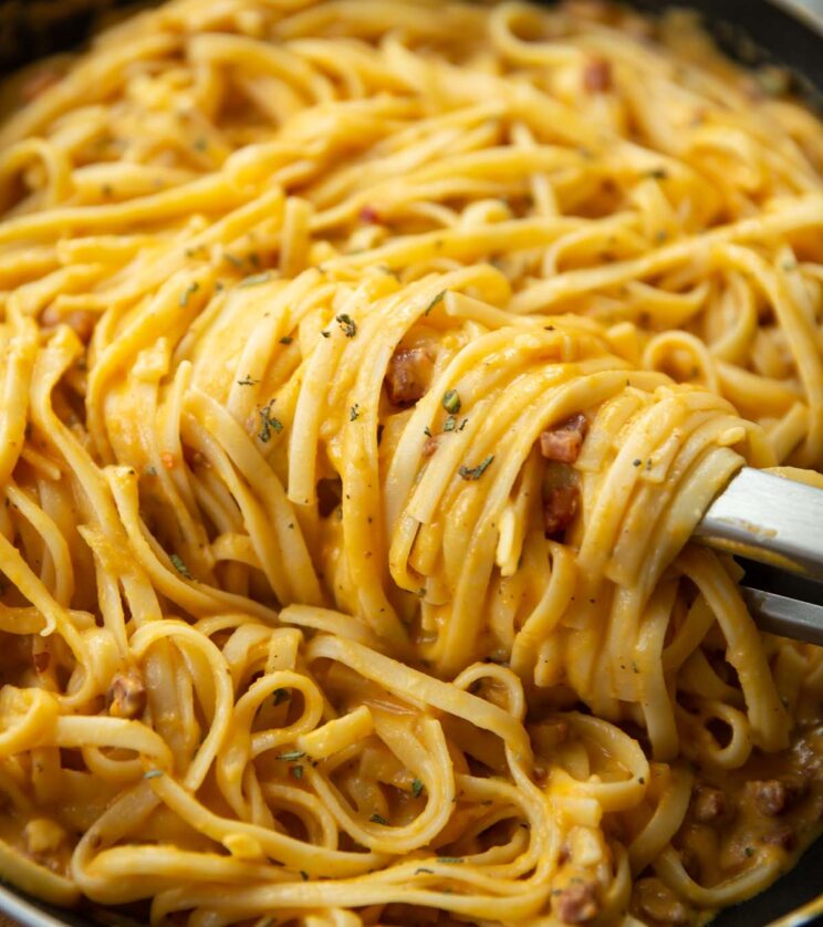 close up shot of tongs twirling creamy butternut squash pasta in skillet