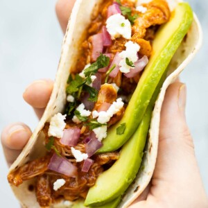 close up overhead shot of hand holding slow cooker chicken taco