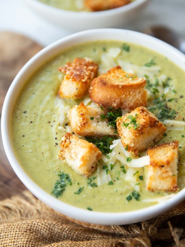 close up side shot of broccoli soup in small white bowl with cheesy croutons