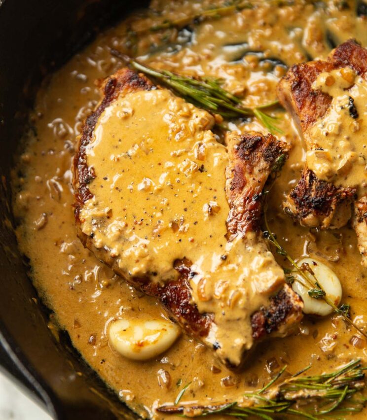 close up shot of pork chop in garlic sauce in cast iron skillet