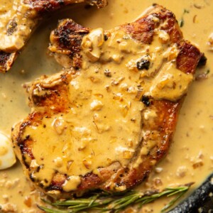 close up overhead shot of pork chop in garlic sauce in cast iron skillet