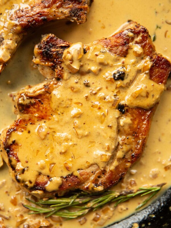 close up overhead shot of pork chop in garlic sauce in cast iron skillet