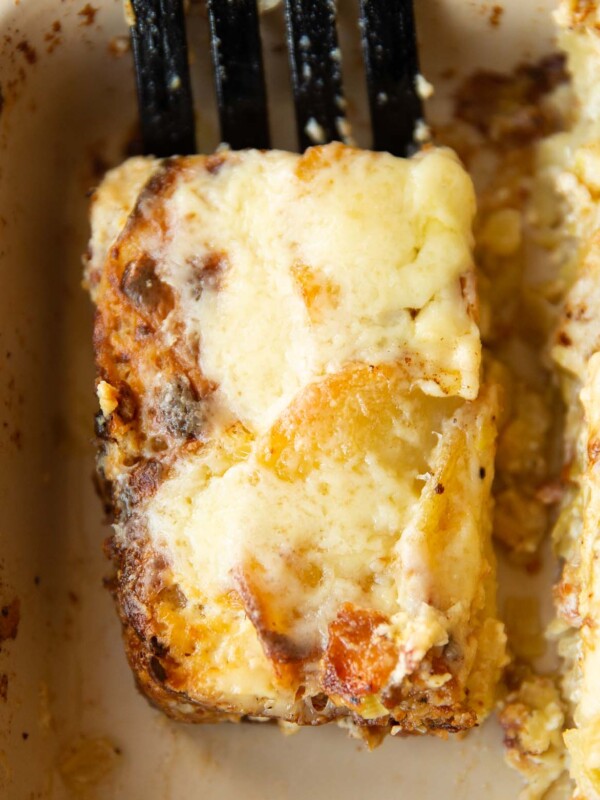 close up overhead shot of black spatula lifting portion of leek bacon potato gratin