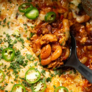 overhead close up shot of black serving spoon digging into pot of chili mac