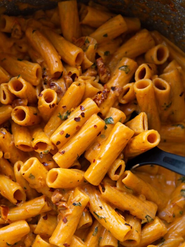 overhead shot of black serving spoon digging into pot of spicy rigatoni