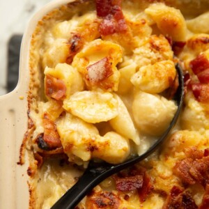 close up shot of cauliflower cheese pasta bake with black serving spoon digging in