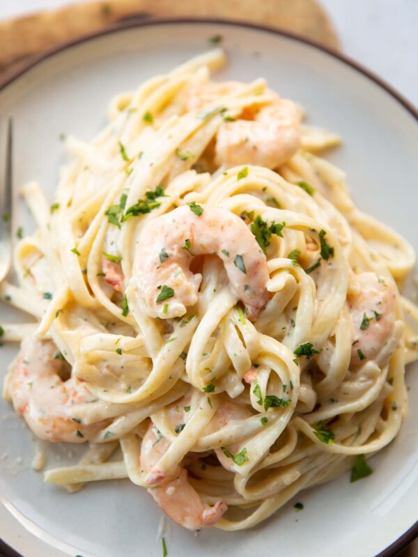 close up shot of creamy prawn linguine on small white plate with silver fork on the side