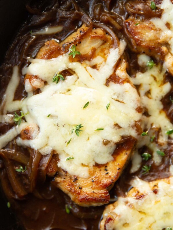 close up shot of french onion pork chop in skillet garnished with fresh thyme