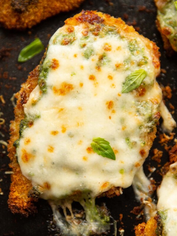 close up overhead shot of baked pesto chicken fresh out the oven on black baking tray