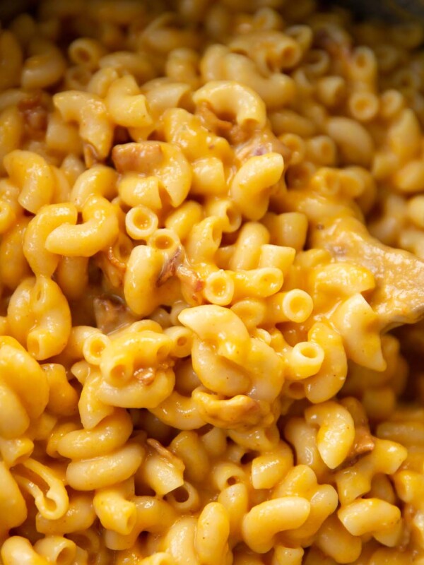 close up shot of butternut squash mac and cheese in pot with wooden spoon digging in