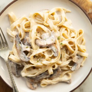 overhead shot of mushroom tagliatelle on small white plate with silver fork