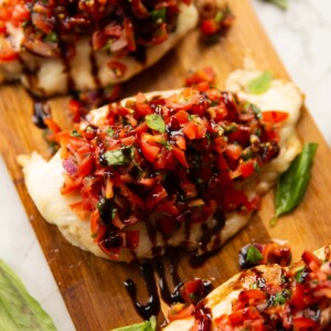 close up shot of chicken bruschetta on wooden board with fresh basil as garnish