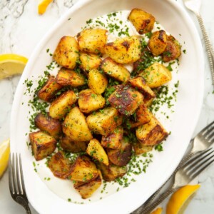 overhead shot of Greek roasted potatoes on whipped feta in white serving dish