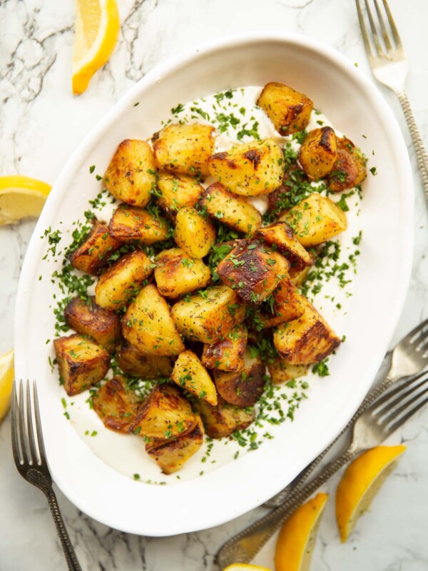 overhead shot of Greek roasted potatoes on whipped feta in white serving dish