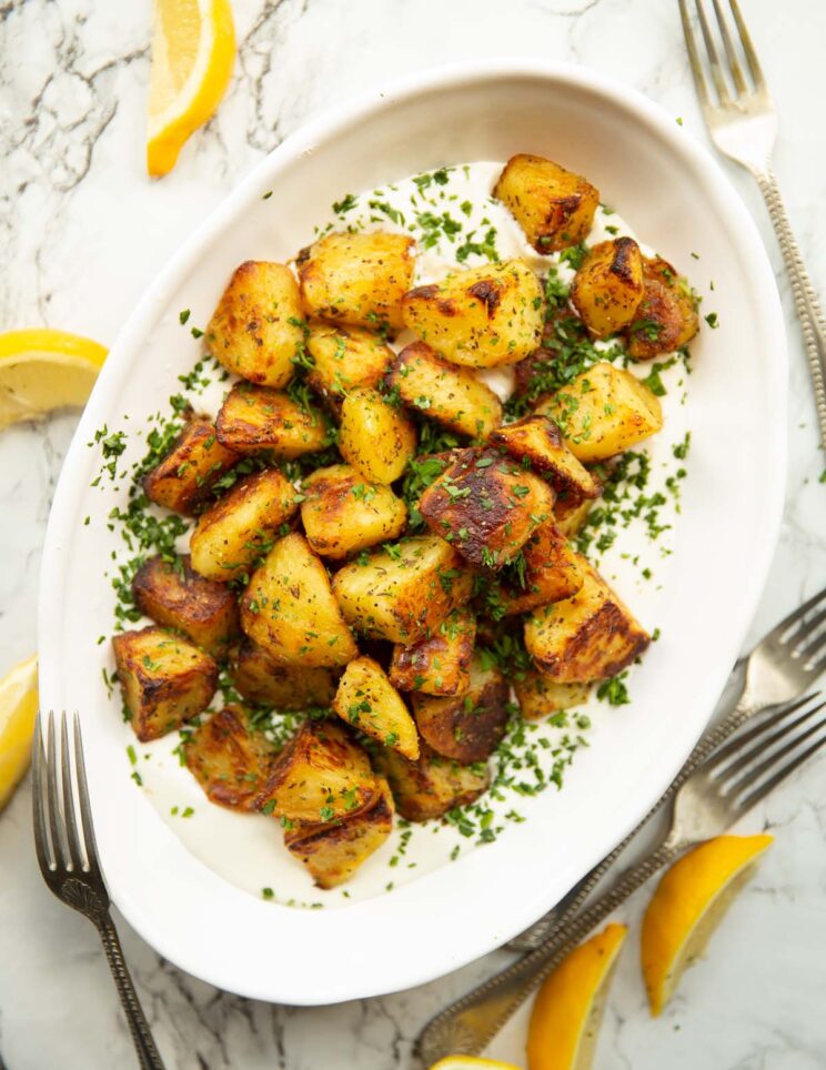 overhead shot of Greek roasted potatoes on whipped feta in white serving dish