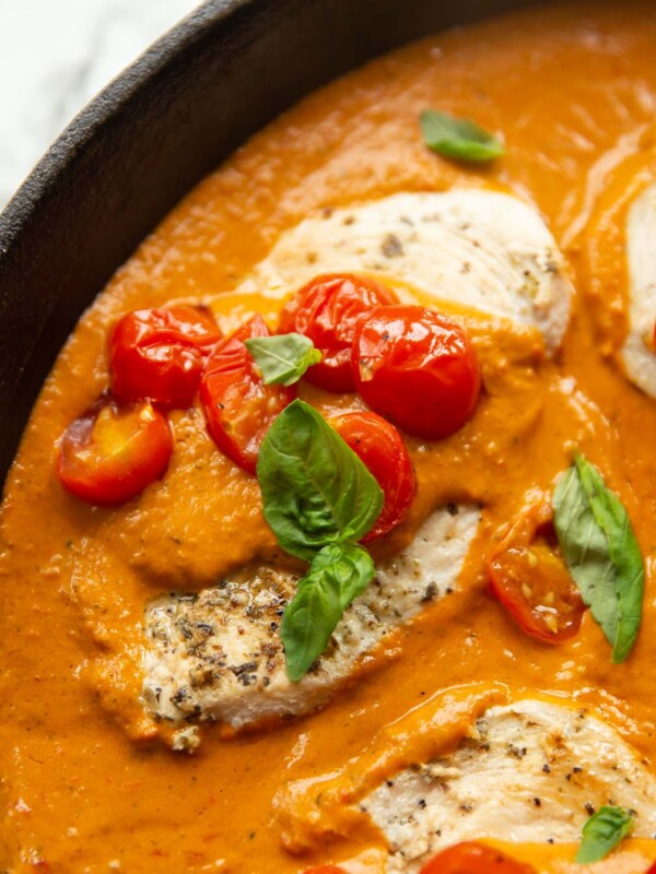 close up shot of creamy tomato chicken in pan garnished with basil