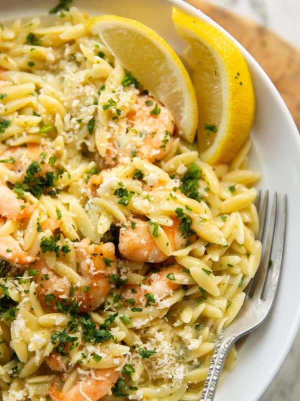 close up shot of garlic butter orzo in large white plate with silver fork