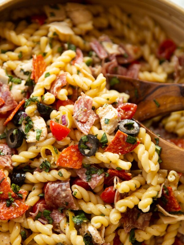 close up shot of Italian sub pasta salad in salad bowl with wooden salad tossers