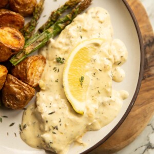 close up shot of lemon thyme pork chop on small white plate with potatoes and asparagus