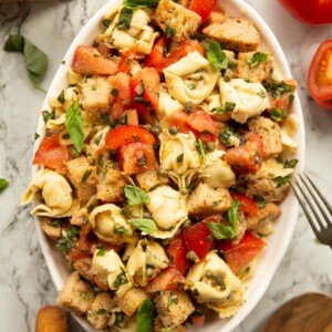 overhead shot of Panzanella tortellini salad in large white dish on marble background