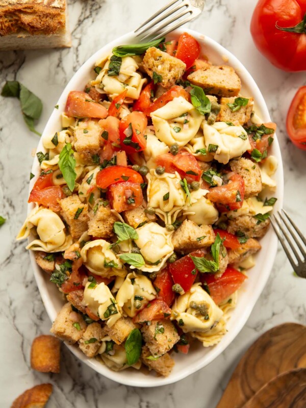 overhead shot of Panzanella tortellini salad in large white dish on marble background