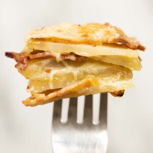 close up shot of half a cheese and bacon potato stacks on silver fork